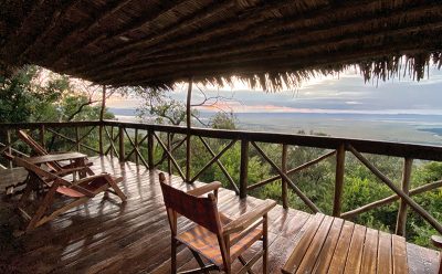 Wooden deck with thatched roof, stunning views from one of the deluxe tents at our Masai Mara safari camp